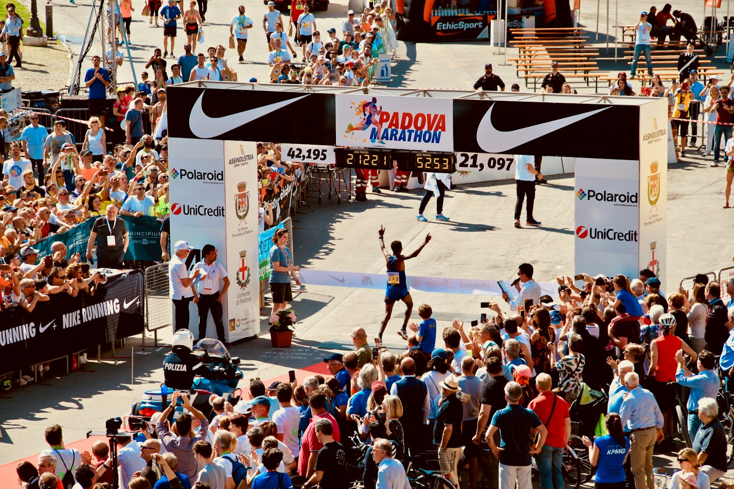 Runner in blue celebrates crossing the marathon finish line.